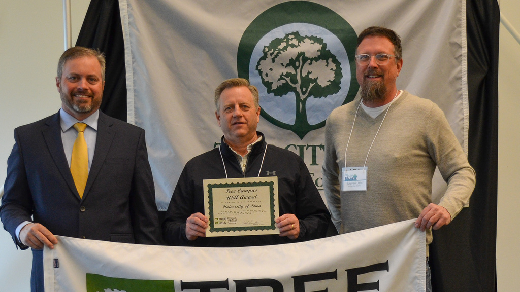 Members of Landscape Services hold up a Tree Campus USA and certificate celebrating their status as UI's Tree Campus Higher Education